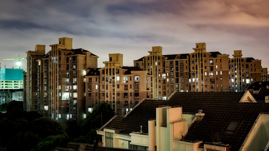 A vibrant cityscape featuring illuminated apartment buildings under the night sky.