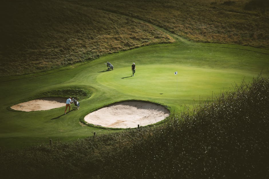 Golfers on a sunny day at Étretat Golf Course, France, surrounded by lush greens and sand traps.