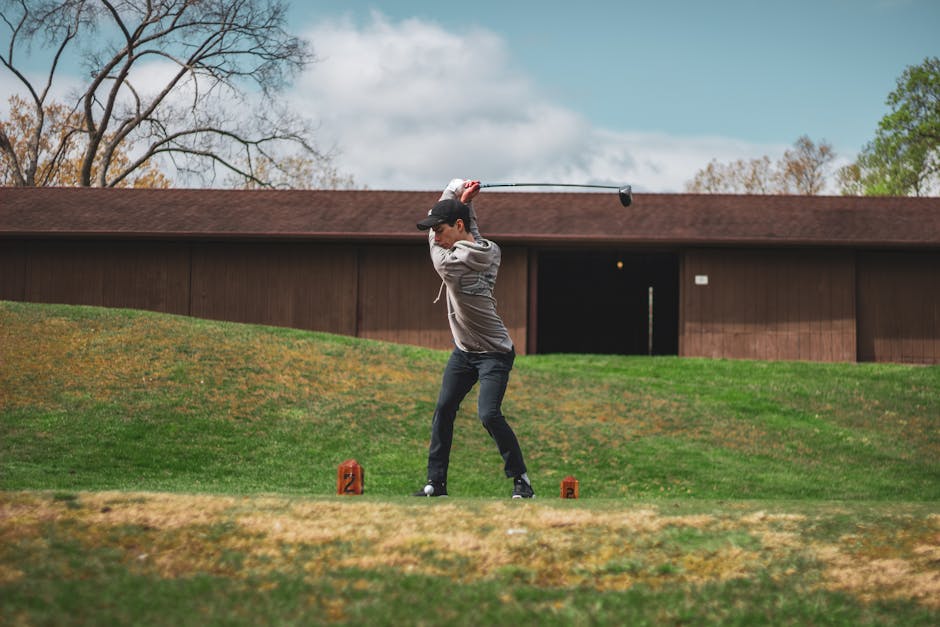 Caucasian man in action on the golf course, swinging club on a sunny day.
