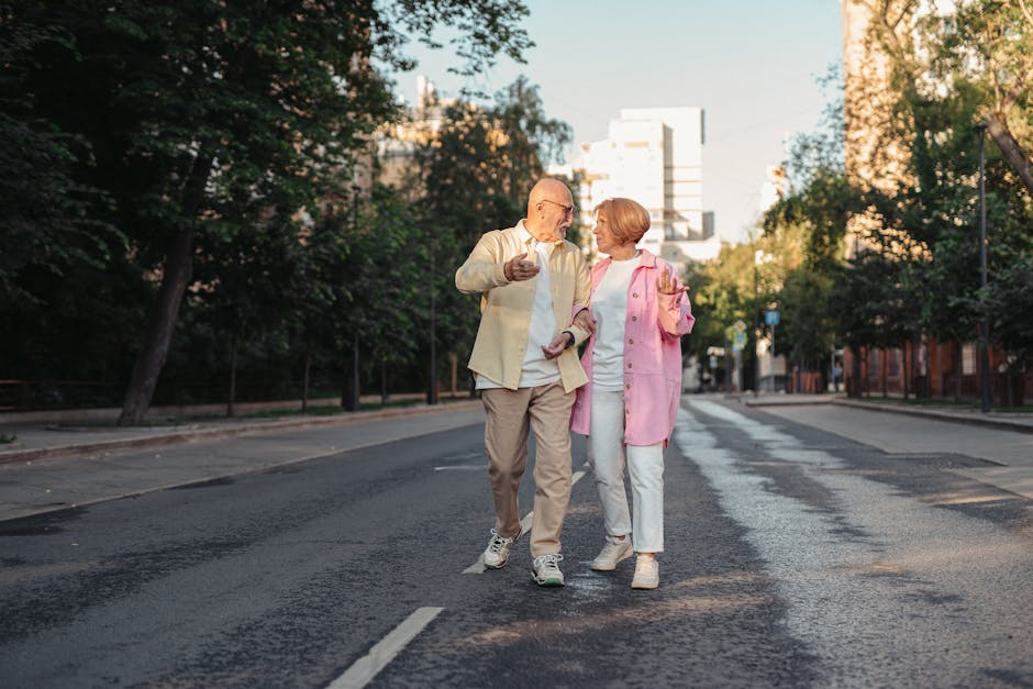 Happy elderly couple strolling down a sunny city street, enjoying a warm day outdoors.