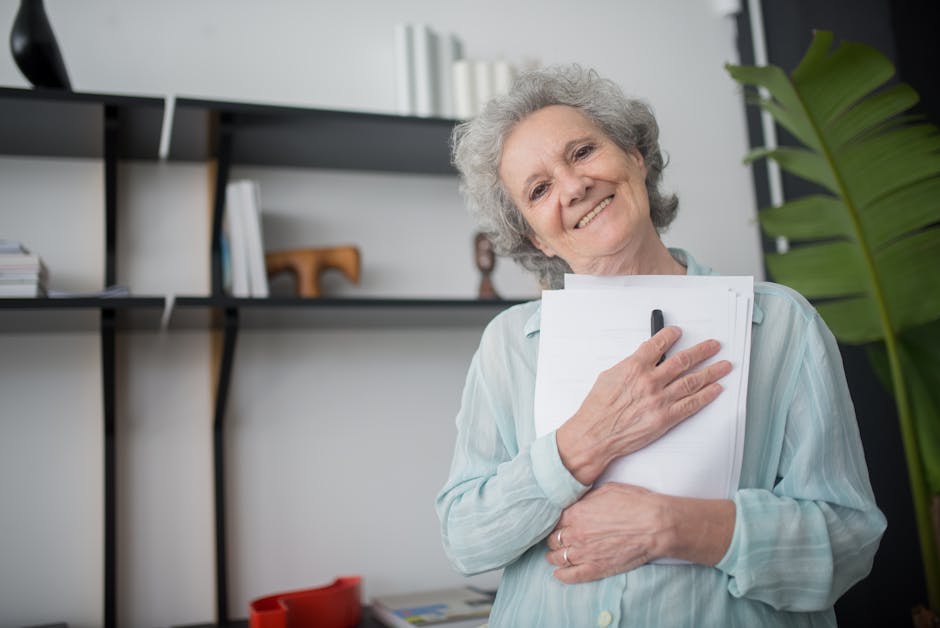 Senior woman smiling while holding papers indoors, showcasing happiness and contentment.