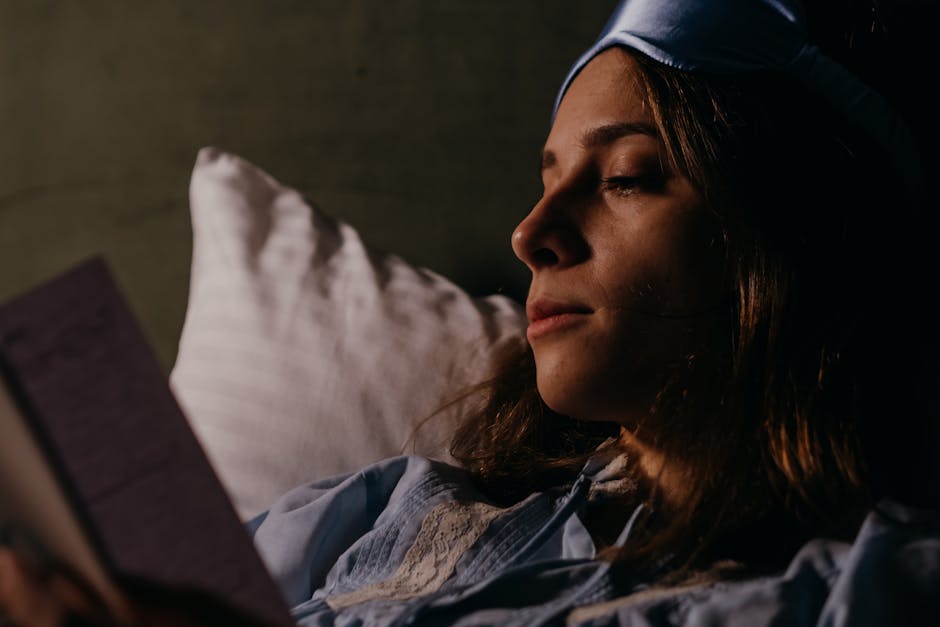 Woman reading in bed with a blue sleep mask, cozy nighttime routine.