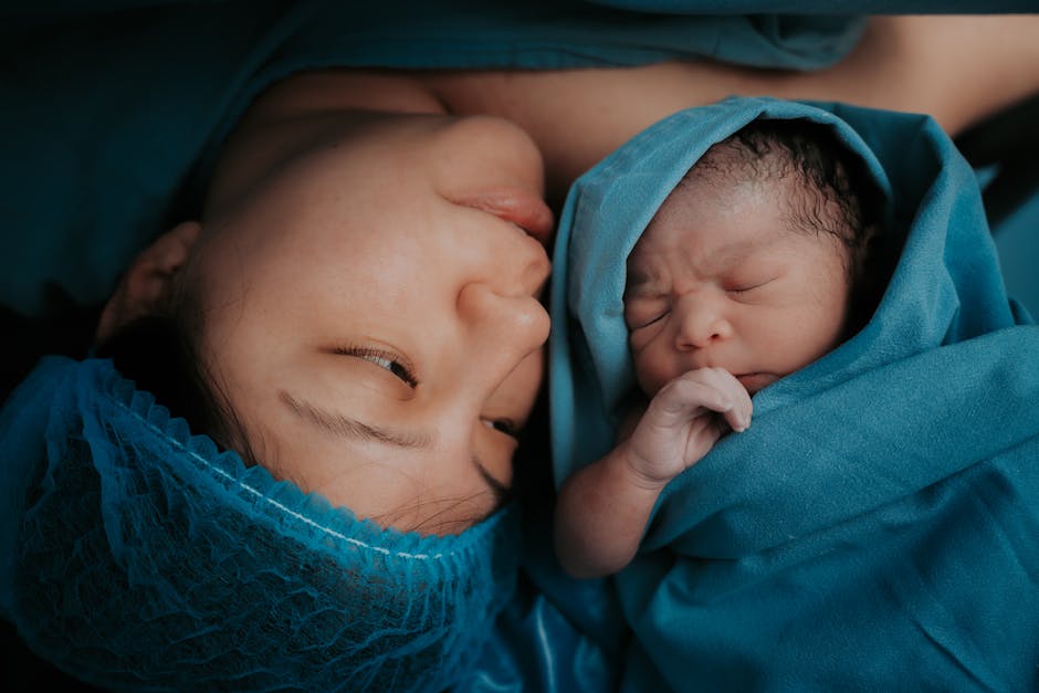 A touching image of a mother and her newborn baby wrapped in blue medical blankets.