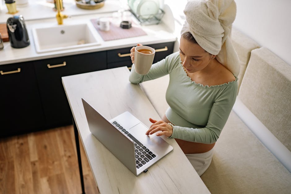 Expectant mother enjoying coffee while working remotely on her laptop.