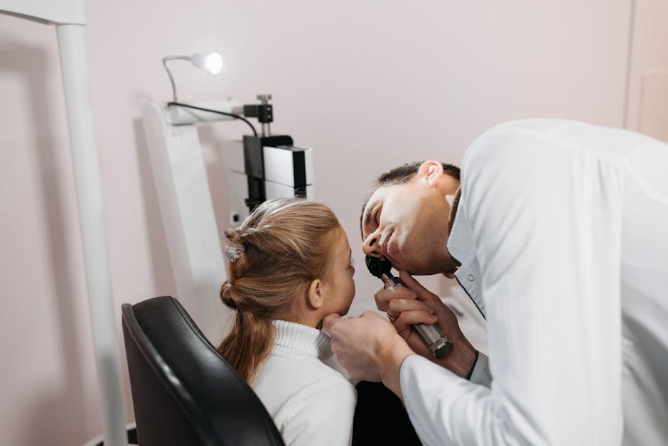 A doctor examines a young girl's ear during a medical appointment in a clinic.