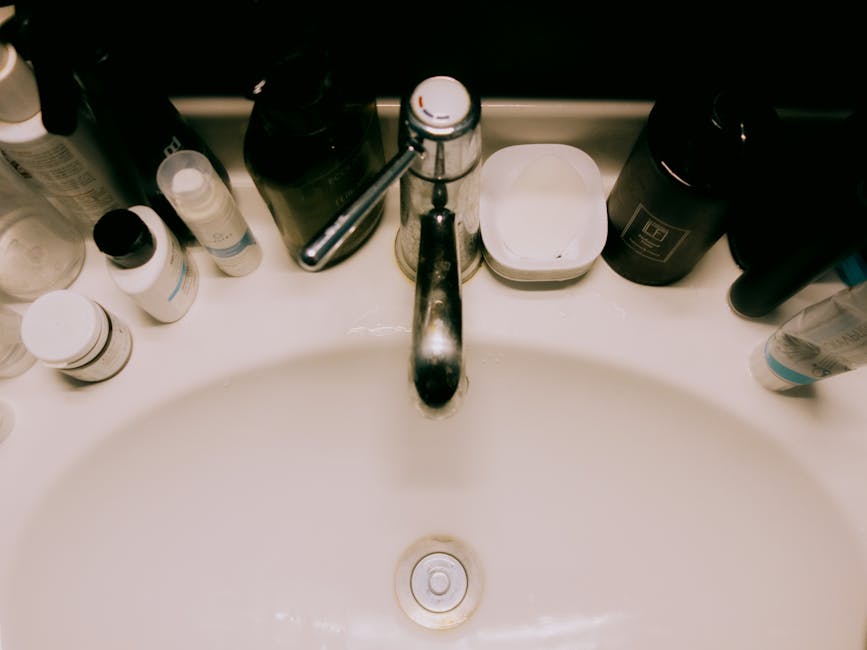 Overhead view of a bathroom sink surrounded by various toiletries, offering a modern minimalist aesthetic.