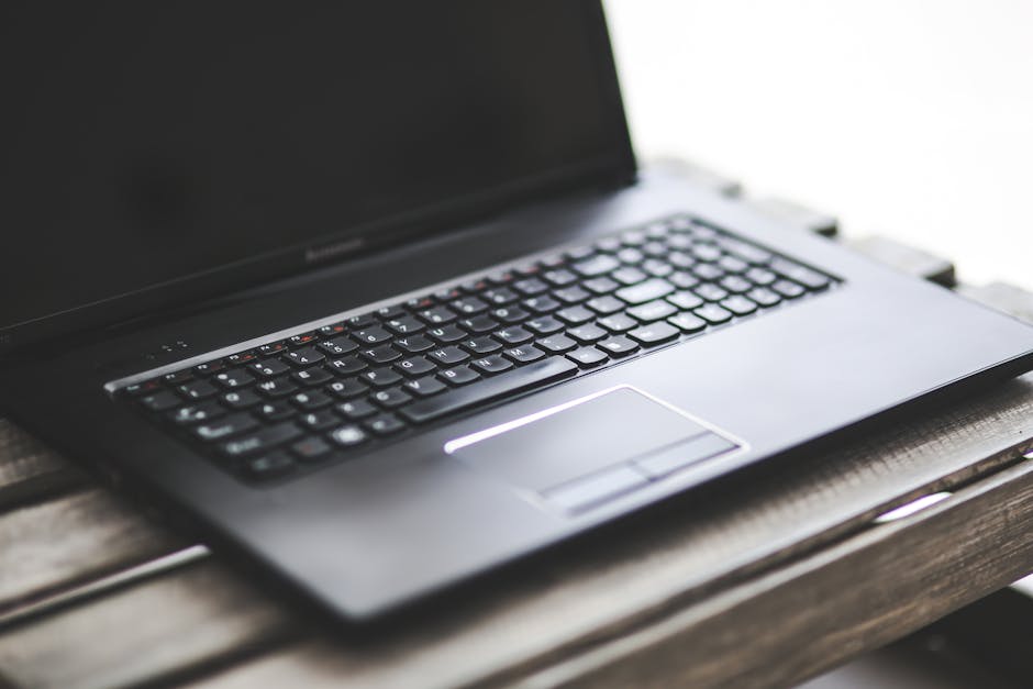 Sleek black laptop resting on a rustic wooden table. Ideal for workspaces.
