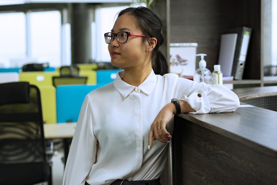 Side view of an Asian woman in a modern office environment, displaying professional demeanor.