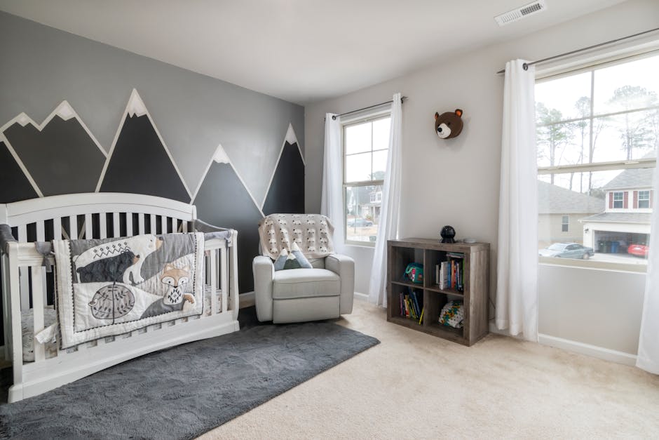 Stylish nursery room featuring mountain mural, comfortable chair, and cozy crib setup.