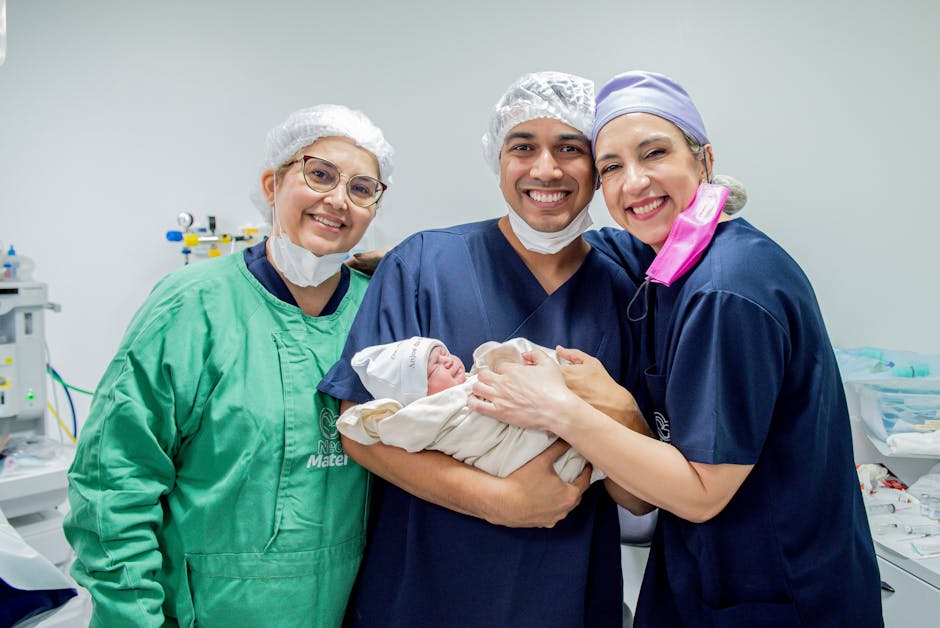 Smiling healthcare professionals holding a newborn baby in a hospital room.