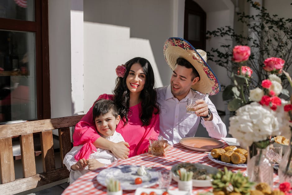 A joyful Hispanic family celebrates together outdoors with traditional food and decor.