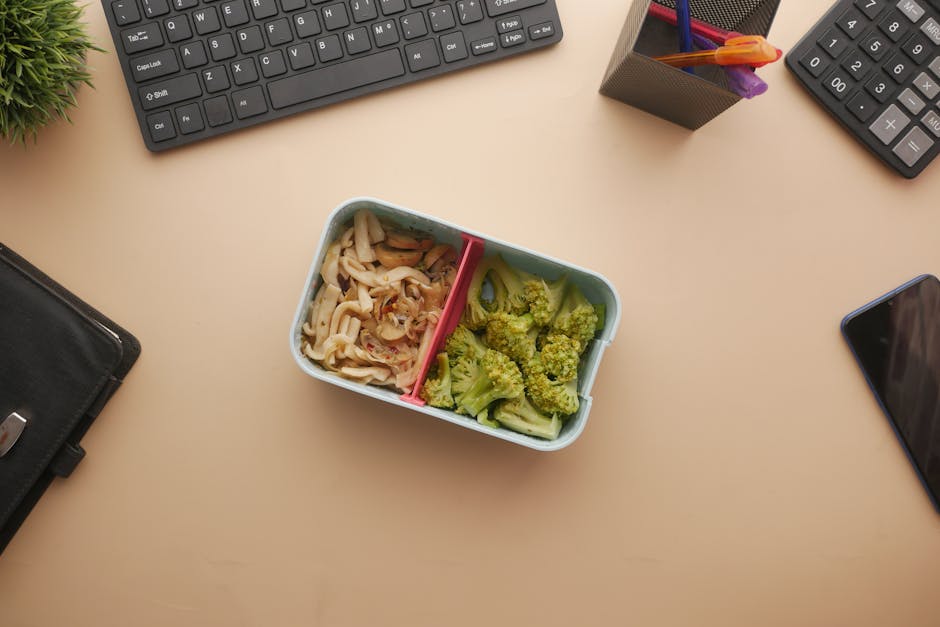 Lunchbox with broccoli and mushrooms on an office desk setup. Perfect for a healthy work break.