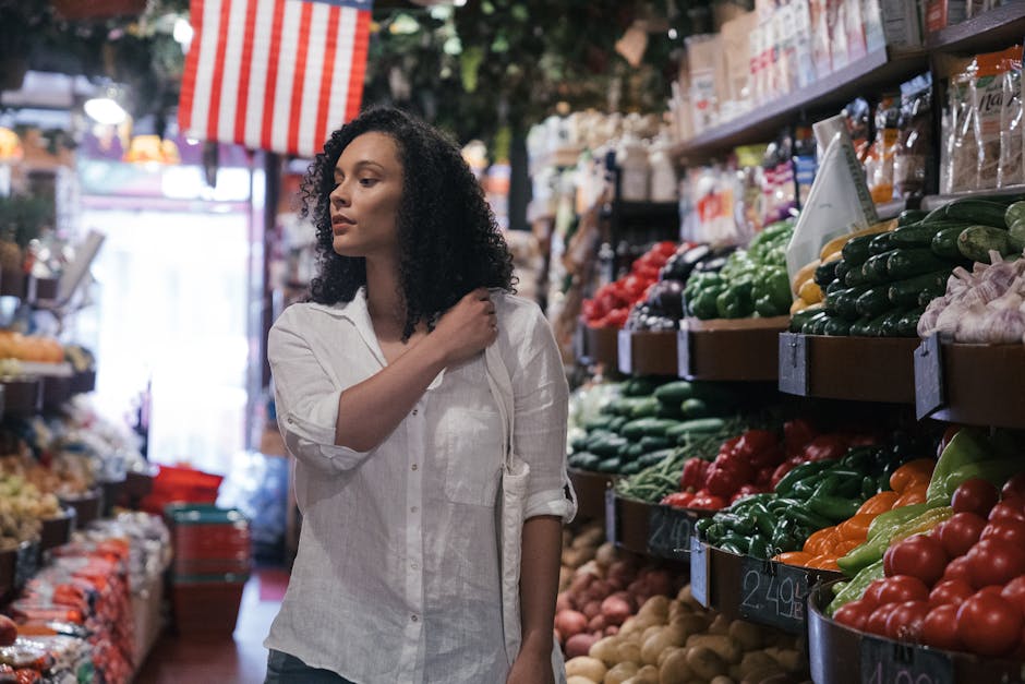 A woman exploring colorful fresh produce in a bustling grocery store aisle.