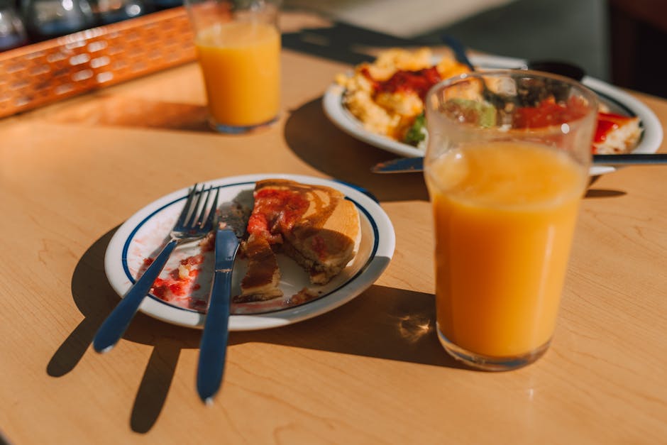 A tasty breakfast featuring pancakes with syrup and a glass of orange juice on a sunny table.