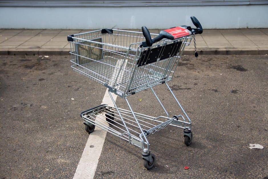 Empty metal shopping cart in a parking lot, positioned on a marked line.