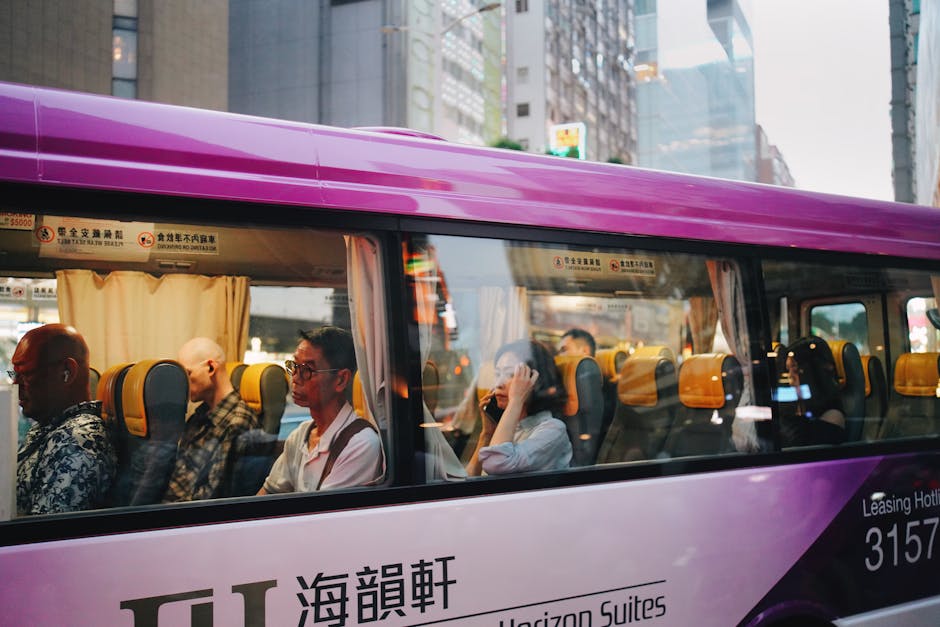 People commuting inside a purple city bus with reflections of an urban landscape.