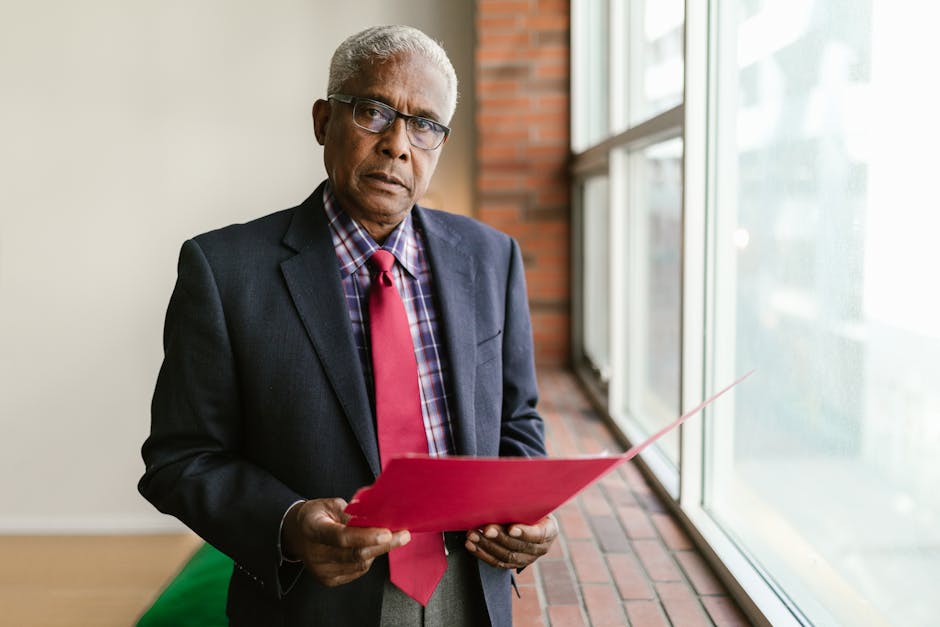Senior African American man in business attire holding a folder in an office setting.