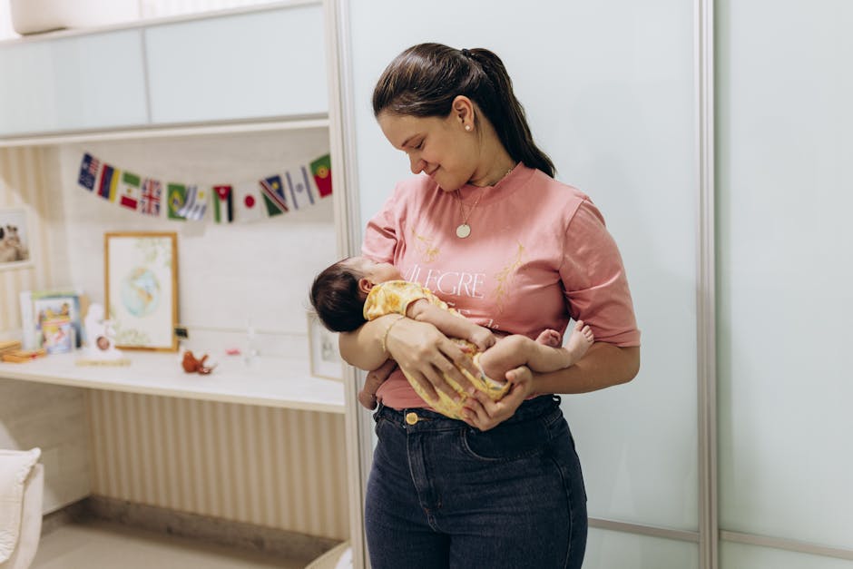 A mother lovingly holds her baby while smiling in a cozy nursery room setting.