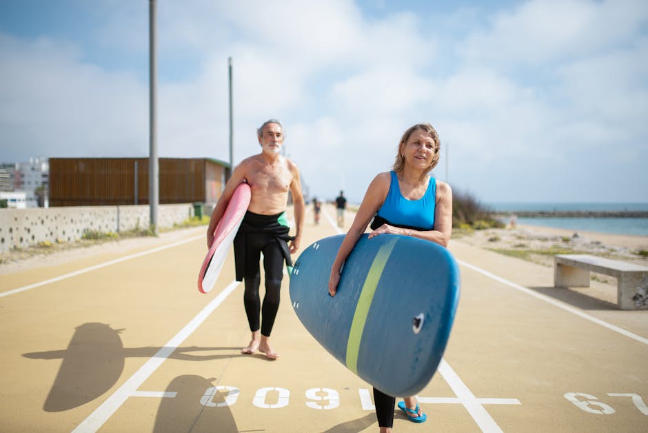 Elderly couple walking with surfboards on a sunny day in Portugal.