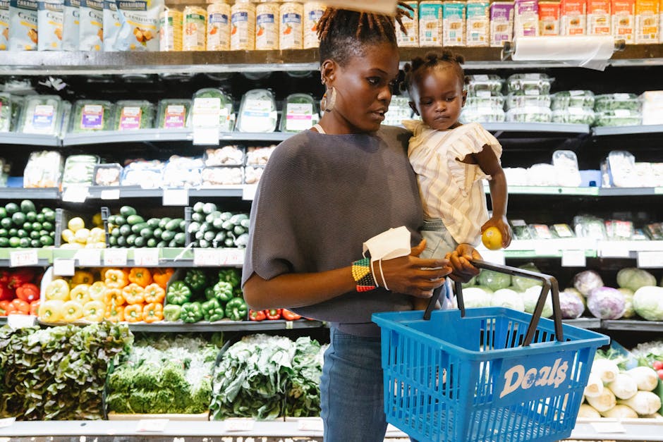 A mother carries her child while shopping in the supermarket's fresh produce section.