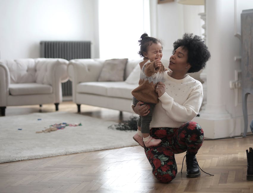 A joyful mother plays with her baby in a cozy, well-lit living room setting.