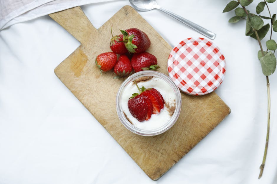 Delicious strawberry yogurt served in a jar on a wooden cutting board, perfect for a healthy snack.