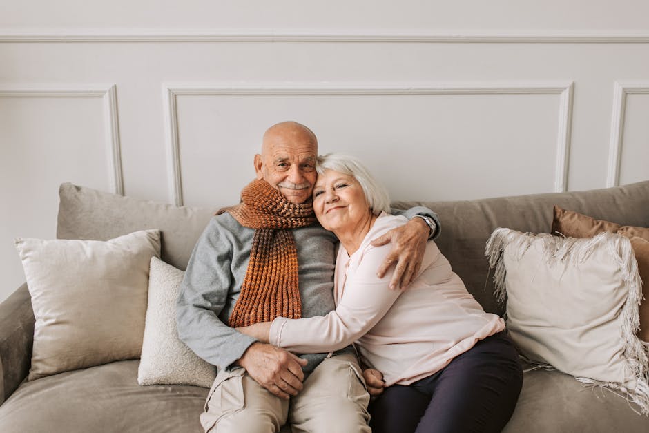 An affectionate elderly couple embracing on a comfortable sofa indoors.