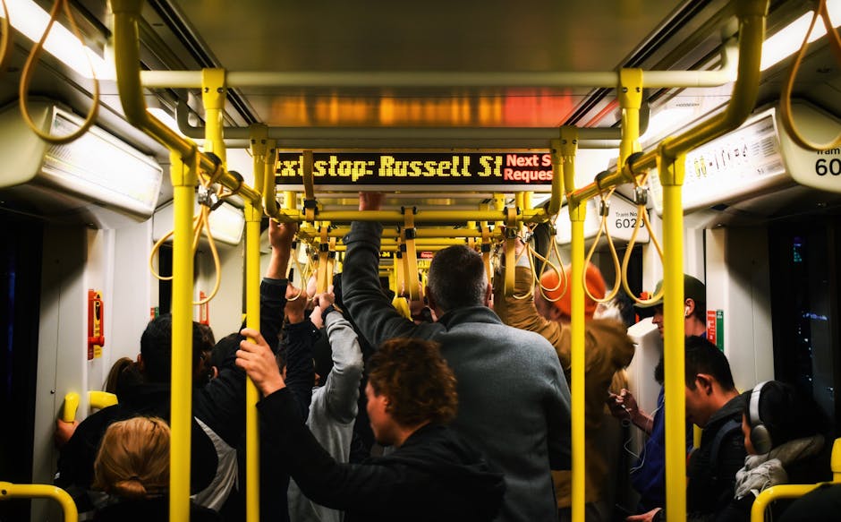 Commuters standing inside a tram in Melbourne with yellow poles and busy atmosphere.