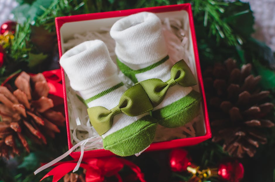 Adorable baby socks with bows in a Christmas-themed gift box surrounded by festive decor.