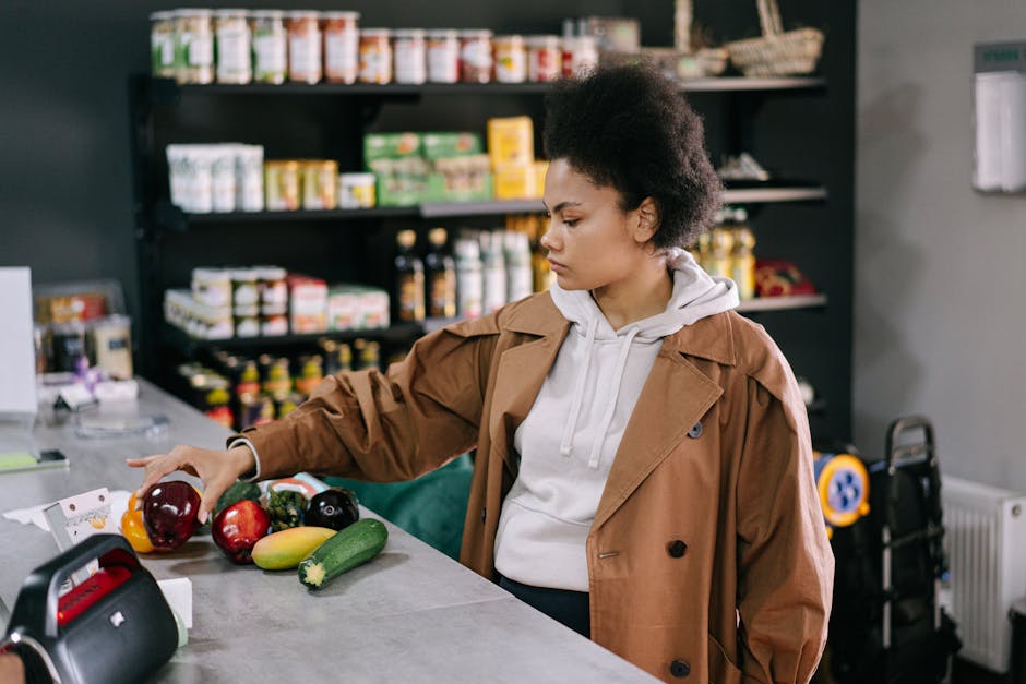 A woman selecting fresh fruits and vegetables at a grocery store with shelves stocked in the background.