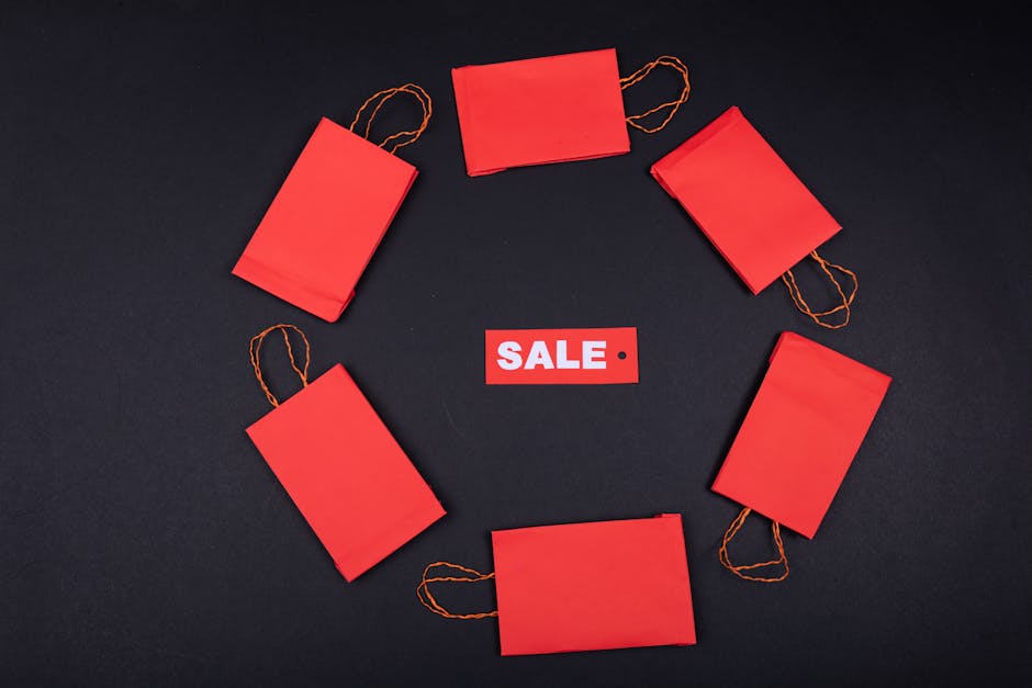 Top view of red paper bags arranged in a circle around a sale tag on a black background.
