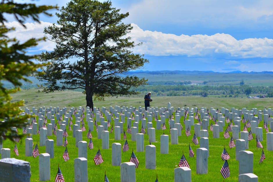 A serene cemetery scene with gravestones and American flags in Custer, SD, under a clear blue sky.