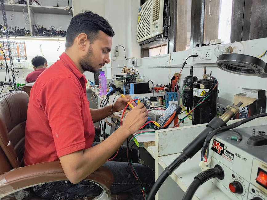 A young technician repairing electronics at a workshop. Focus on concentration and skill.