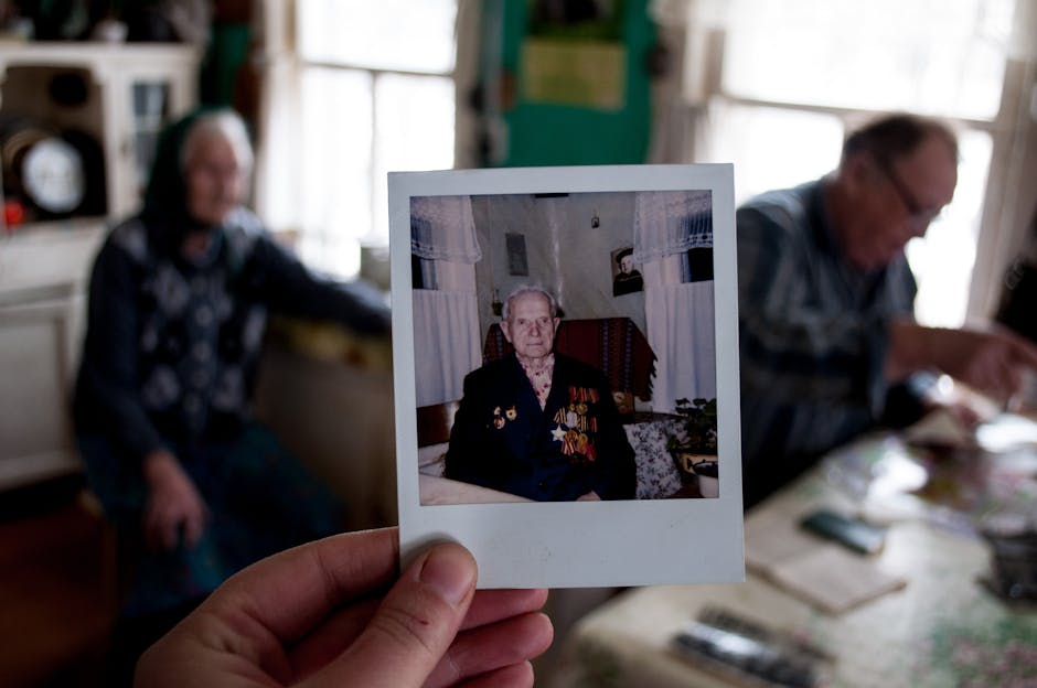 A hand holding a Polaroid picture of an elderly man with medals, capturing a moment of nostalgia and history.