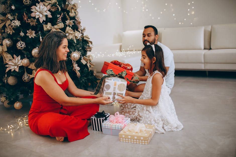 A joyful family exchanging Christmas gifts by a decorated tree indoors.