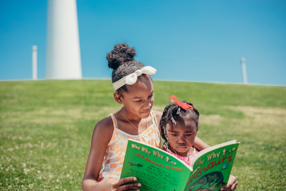 Two young sisters enjoying a book together on a sunny day in the park, emphasizing childhood joy and learning.