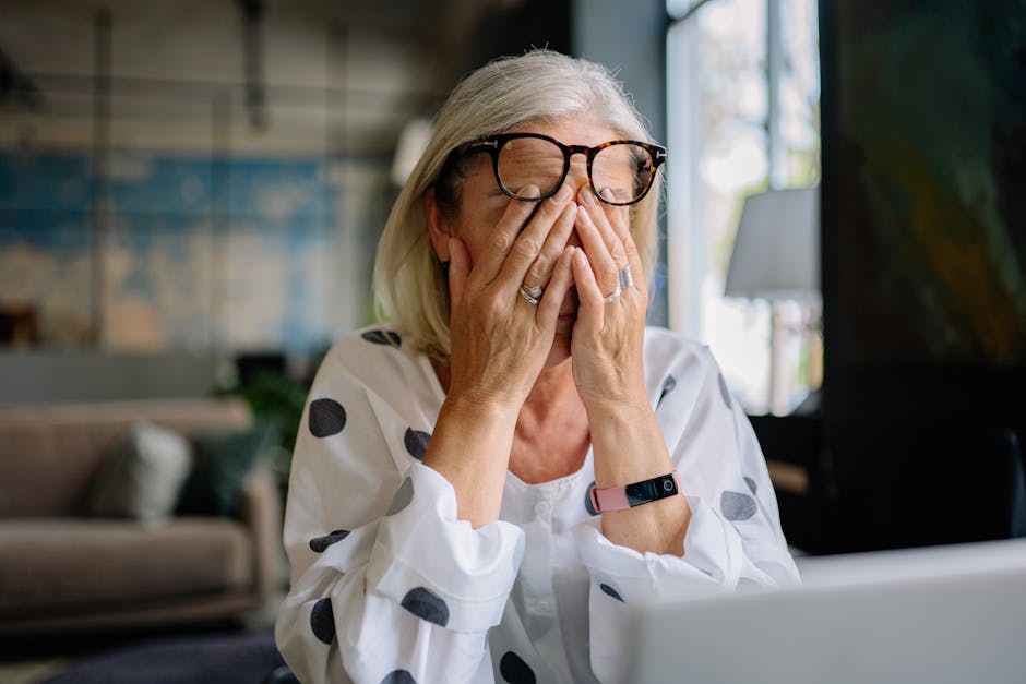 Senior woman experiencing stress indoors, covering face with hands. Reflects emotion and solitude.