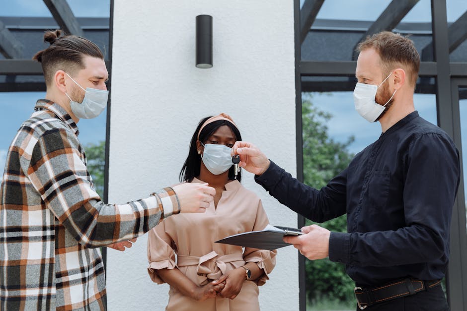 Real estate agent handover keys to a diverse couple wearing face masks, outdoors.