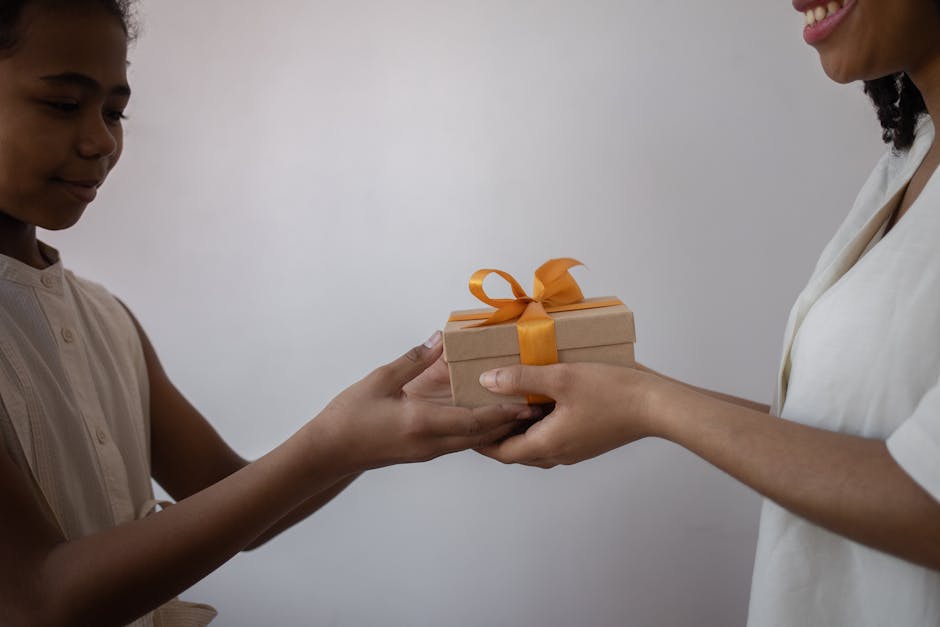 A joyful moment as a mother hands a gift to her smiling daughter. Perfect depiction of childhood happiness.