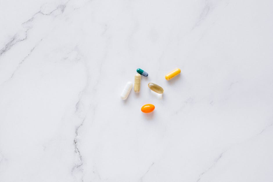 A variety of colorful pills arranged on a white marble surface, representing healthcare.