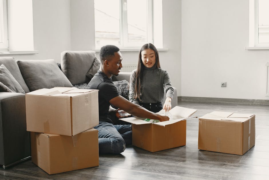 Happy couple unpacking moving boxes in their new apartment living room.