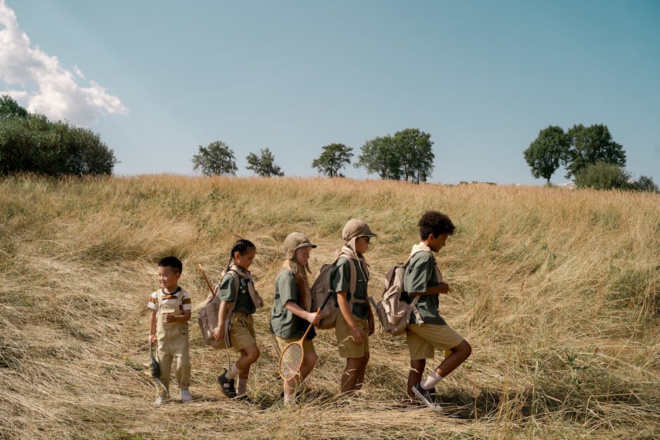 Group of kids exploring a sunny field on an outdoor adventure at summer camp.