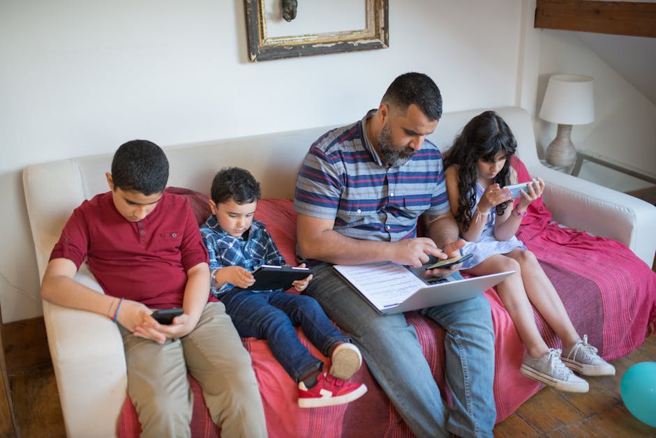 Father and children using gadgets on a sofa, balancing work and leisure.