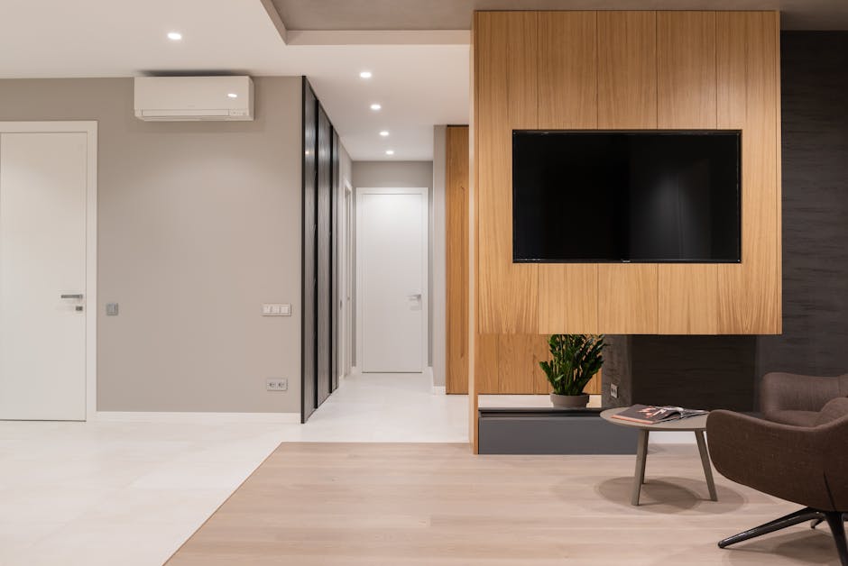 Apartment interior with armchairs and table next to TV on wall and door