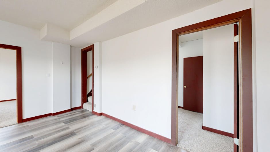 Spacious empty room with modern wooden flooring and brown door frames.