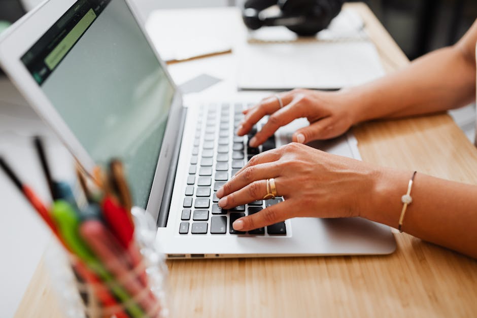 A person typing on a laptop at a wooden desk, showcasing a productive work environment.