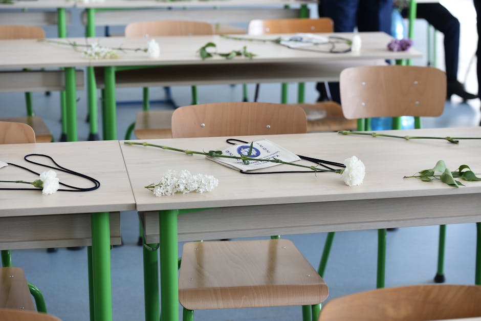 Rows of classroom tables with flowers and graduation caps in an indoor setting, suggesting a recent ceremony.