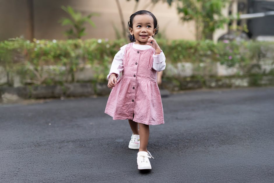 Cute child in pink dress walking confidently outside. Bright, joyful scene.