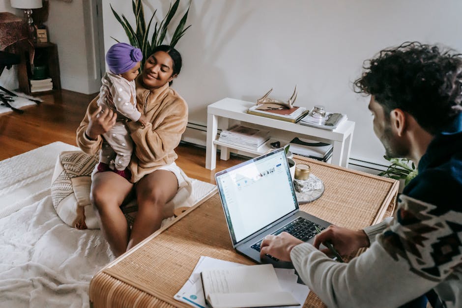 Ethnic man typing on laptop while sitting at table in living room with African American mother and little daughter at home