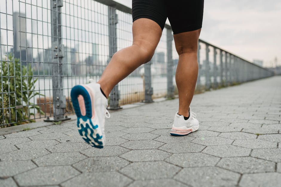 Close-up of legs jogging outdoors with urban backdrop, wearing athletic shoes.